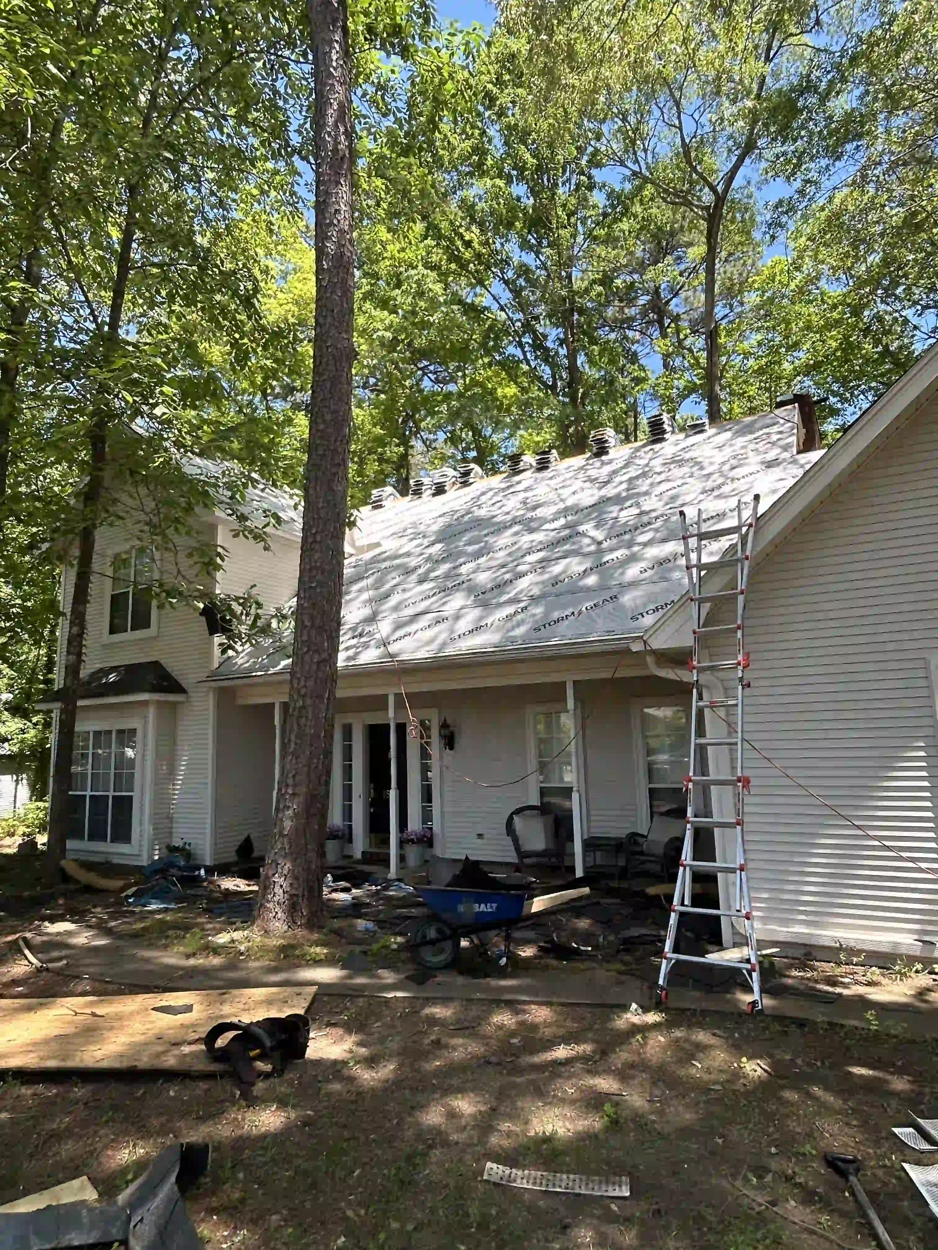 Two-story home with a bay window, upstairs windows, and French doors below a roof being re-covered